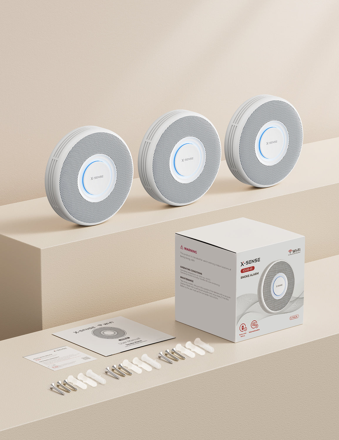 Drei X-SENSE XS0B-iR Rauchmelder mit Verpackung und Zubehör.